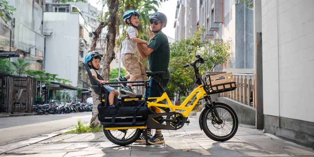 Tern GSD: Electric Cargo Bike and Adult placing a child in rear seat with another child