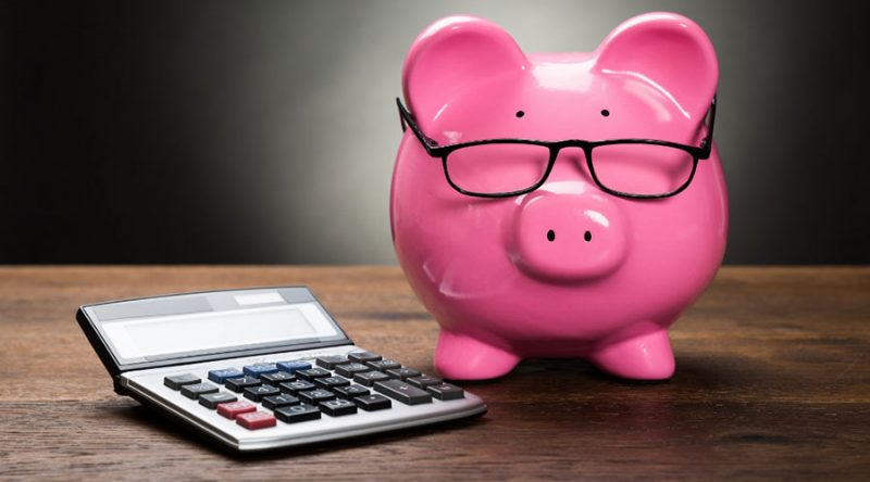a piggy bank with glasses and a calculator on a desk